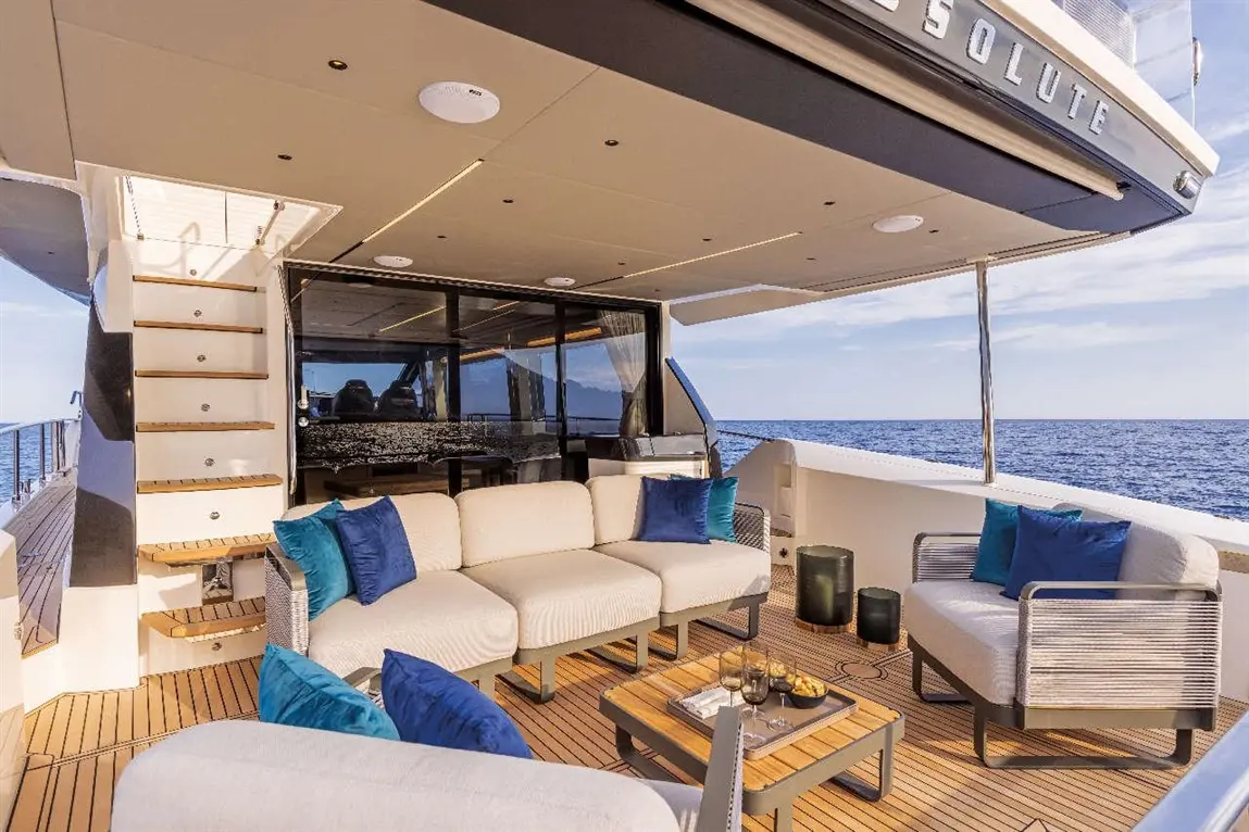 Luxury yacht deck featuring a stylish seating area, wooden flooring, and scenic ocean views, ideal for relaxation and dining.